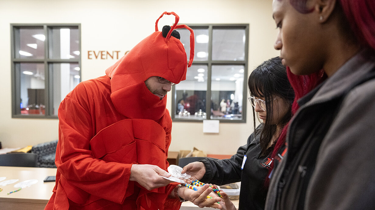 Patrick Allison (left), a NASA scholar and University of Mississippi graduate student in biology, wears a crawfish costume as he demonstrates differences in crawfish species to National TRIO Day attendees. Photo by Thomas Graning/Ole Miss Digital Imaging Services