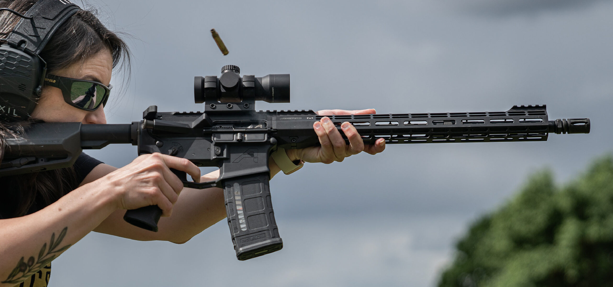 Person taking aim with a semi-automatic rifle with a Freedom Red Dot Sight mounted on top.