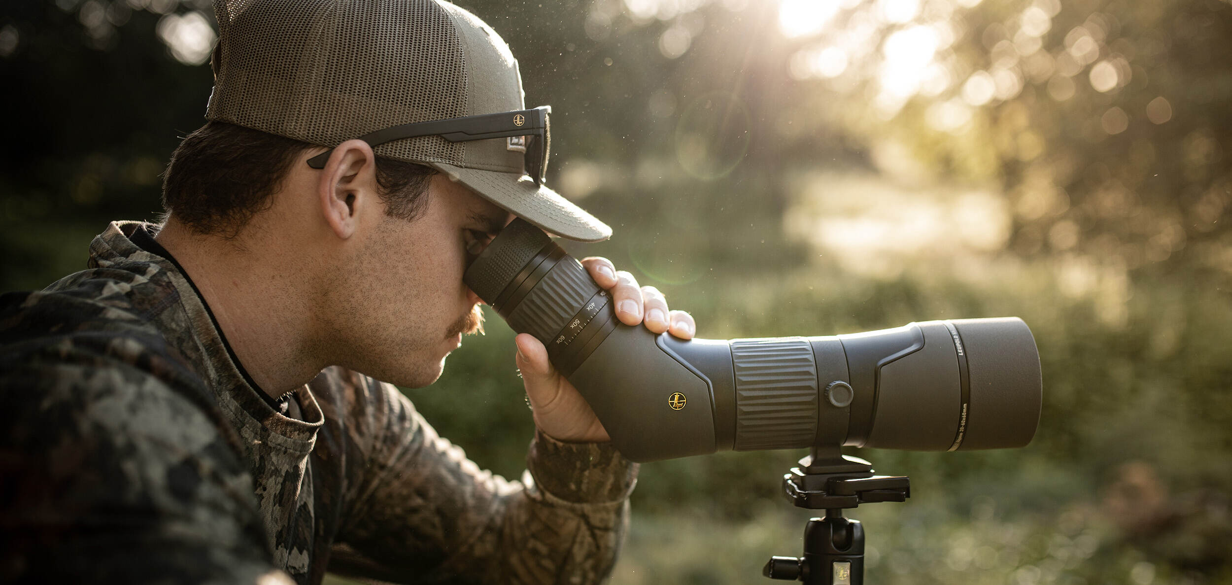 hunter wearing camouflage and hat glassing with leupold binoculars