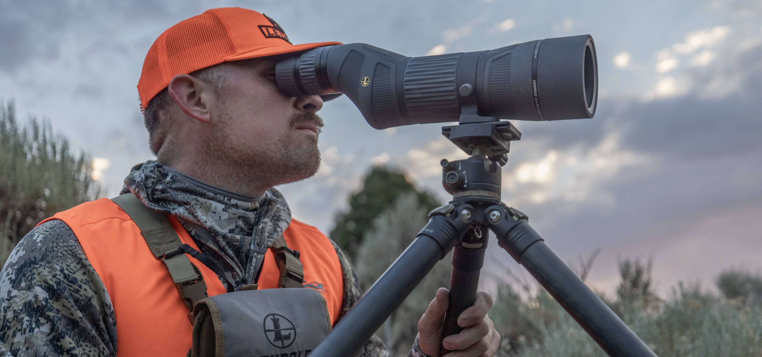 hunter wearing camouflage and hat glassing with leupold binoculars
