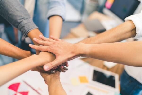 Many hands meeting in middle of office to celebrate small business bonds