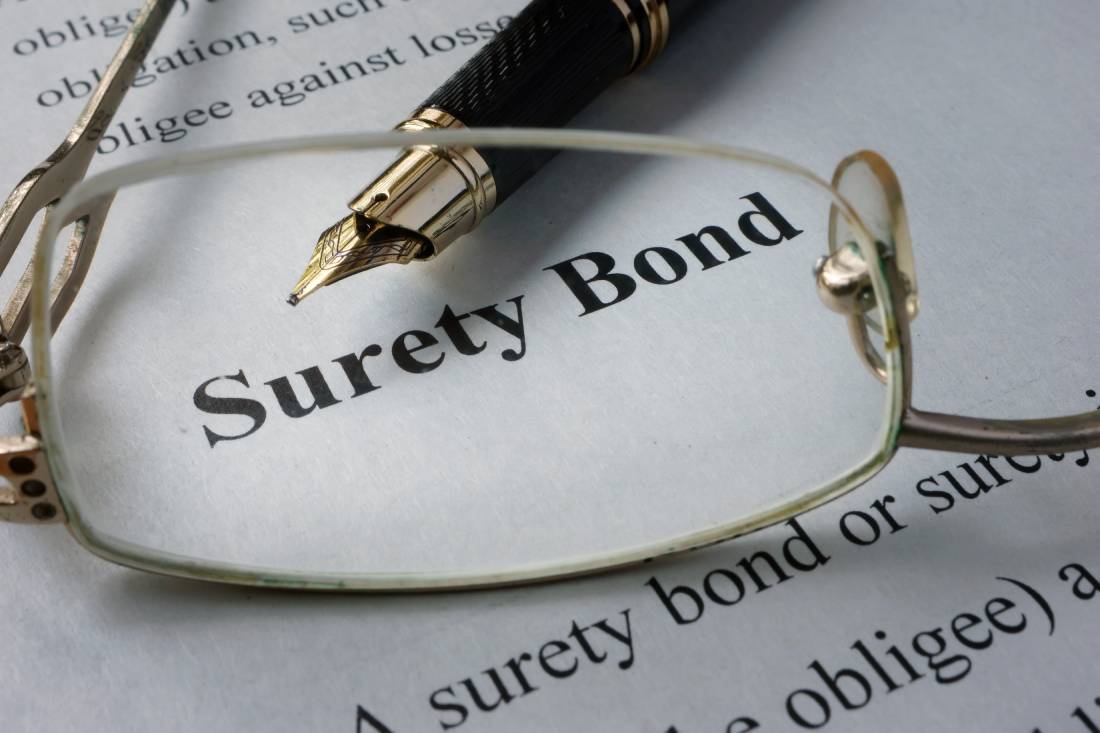 Surety bond documentation with pen and eyeglases laying on top of it