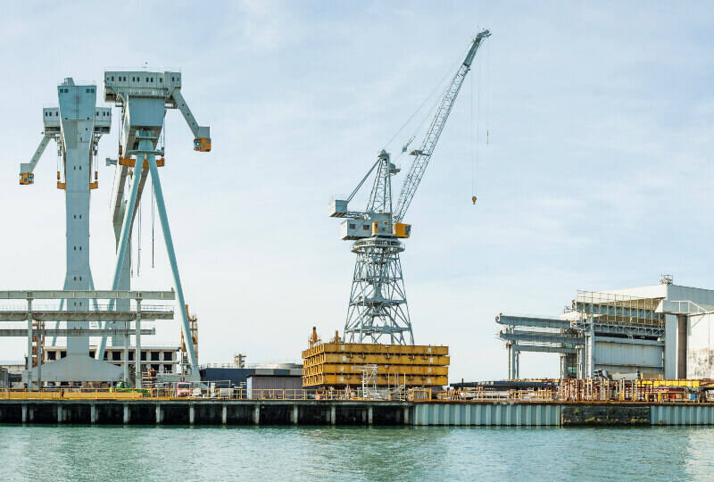 A boatyard atop still waters with a crane centered in the image.