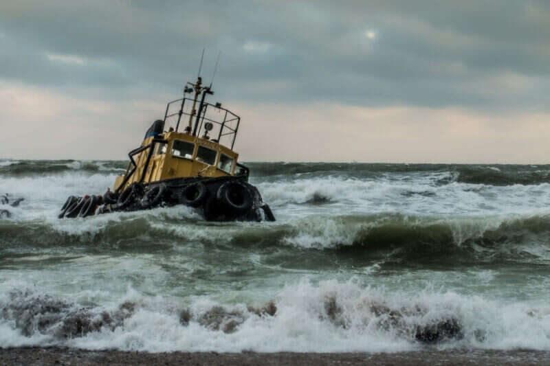 A yellow and black fishing vessel traverses rough waves in the ocean.