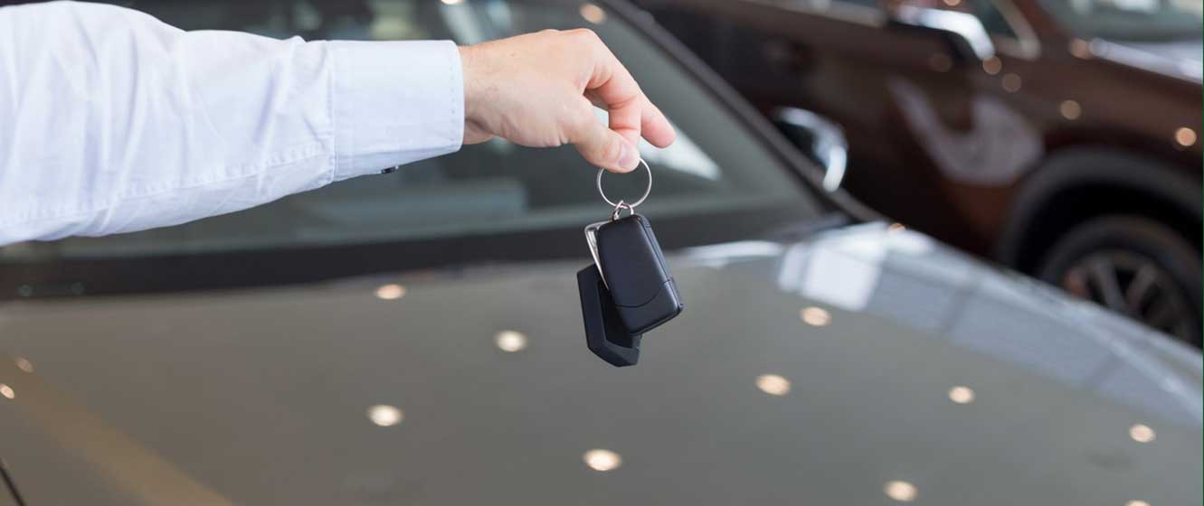 Dealer holding keys to a new car for auto loans.