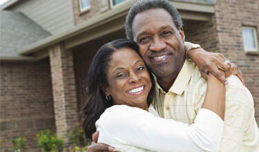 Couple hugging in front of home