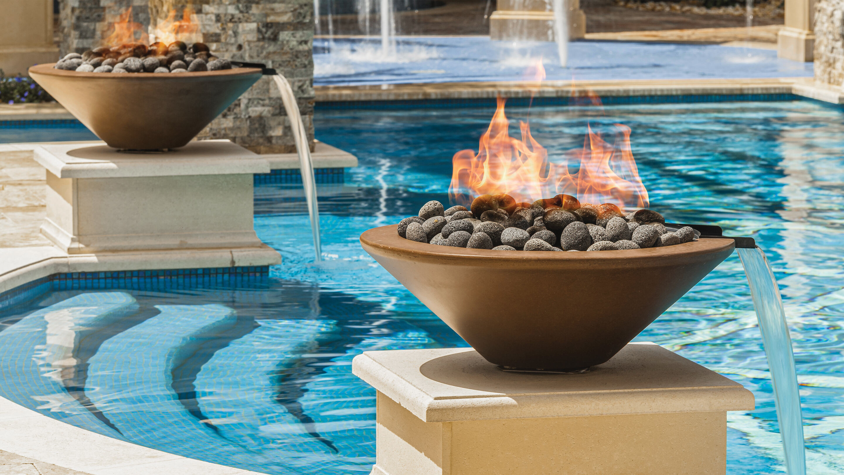 Fire bowl with lava rocks on poolside pedestal