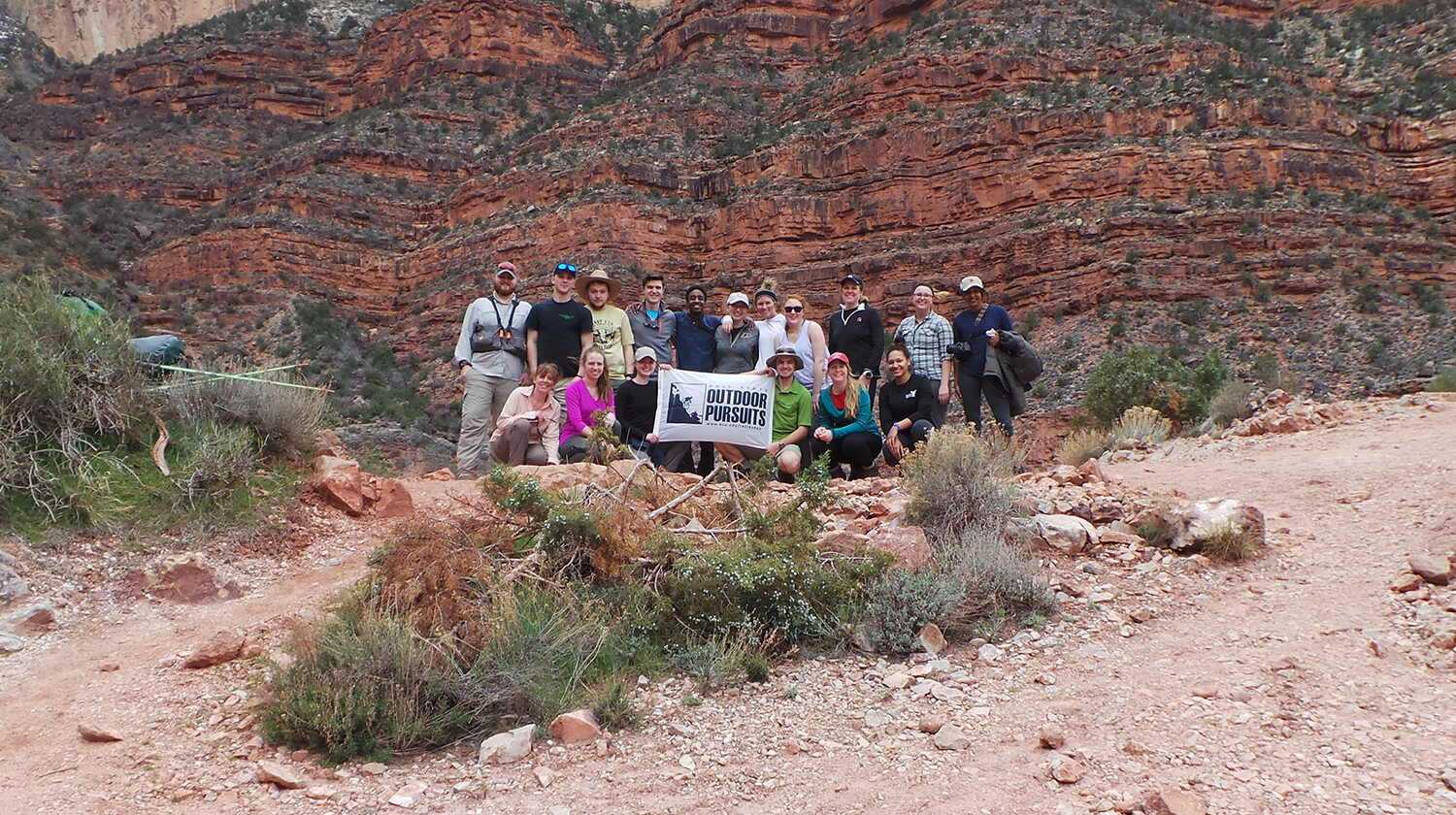 Group of students outdoors, holding a banner for Outdoor Pursuits