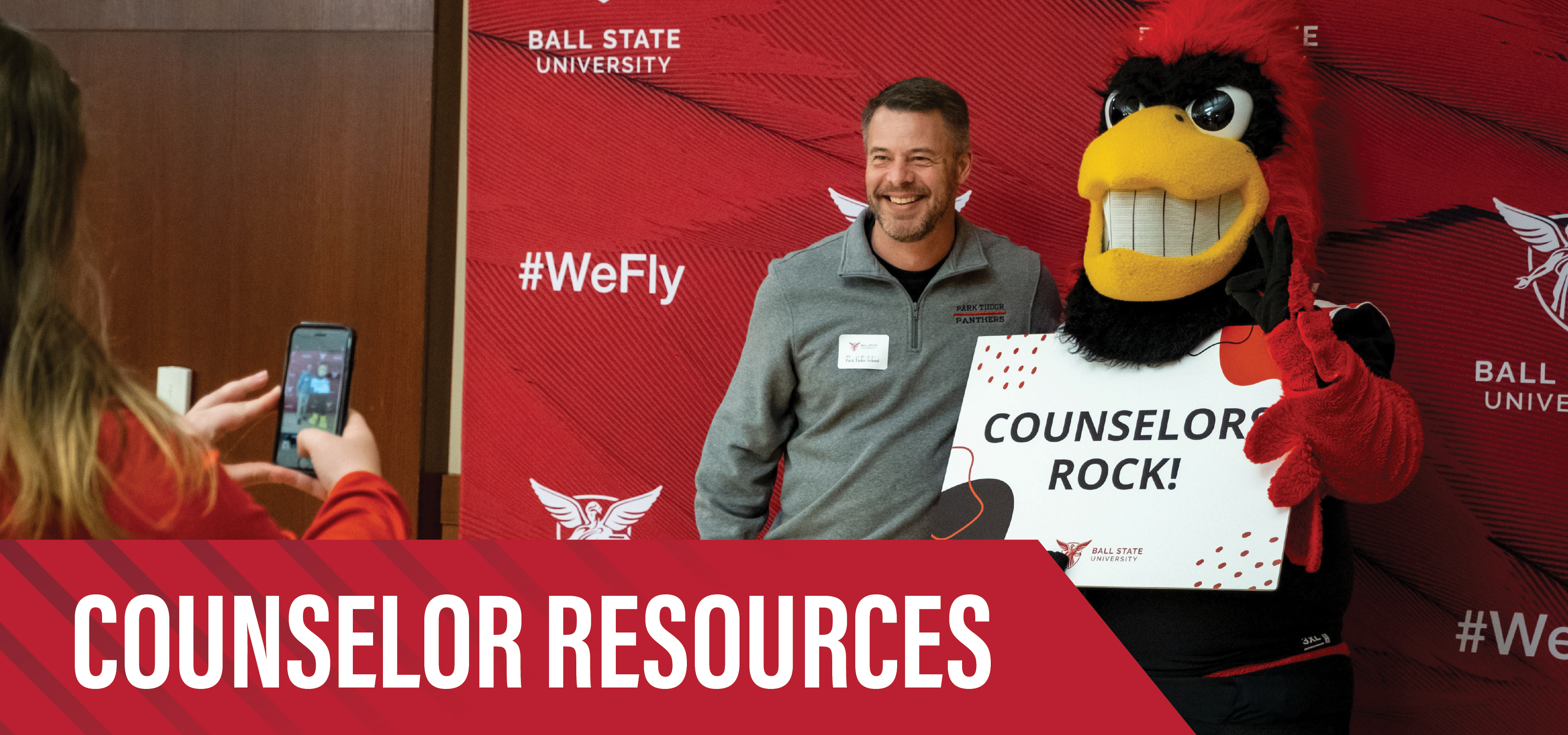 A high school counselor takes a photo with Charlie Cardinal during Counselor Connection Day at Ball State University.