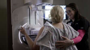Woman receiving mammogram with support of a healthcare professional