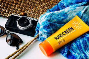Sunscreen, scarf and shades lying on a table