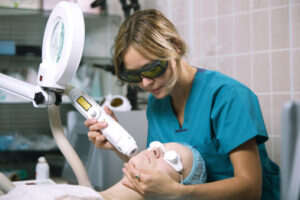 Image of doctor performing laser treatment on patient's face.