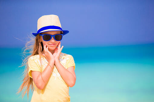 Child Standing in sun wearing hat and glasses for sun rays protection