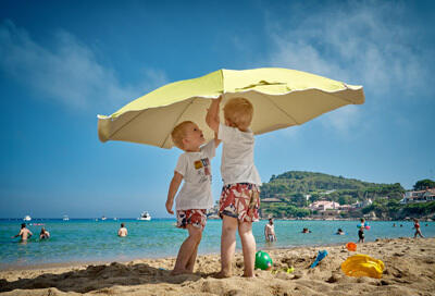 Infants protecting themselves from sun under umbrella 