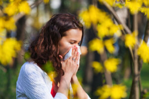 Young woman blowing her nose due to allergy while being in the nature