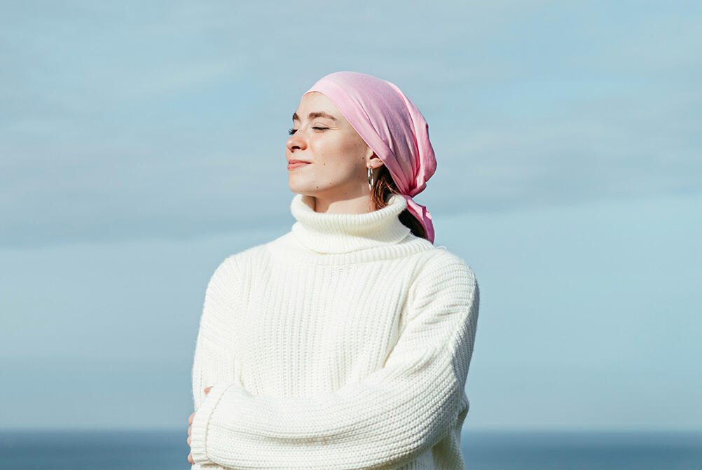 A woman with a pink headwrap looking peacefully off into the distance