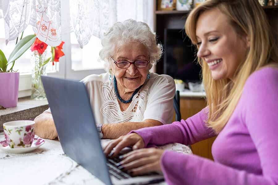 Older woman with her granddaughter looking at a laptop