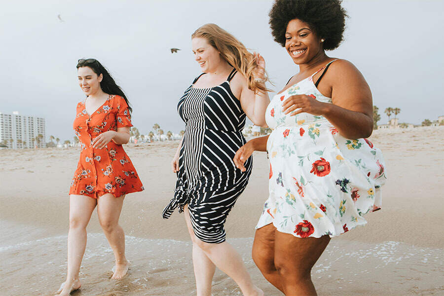 Three women walking on a beach smiling