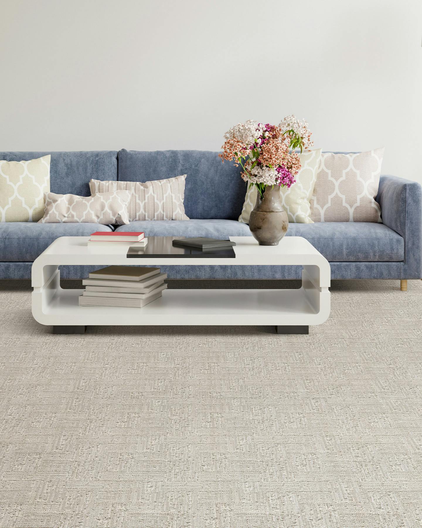 Hitari pale greige carpet style on floor of living room with soft blue couch, flowers, and a coffee table with books