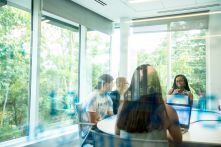 Students work in a glass-walled conference room